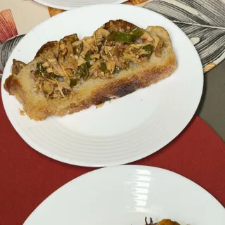 Mesa posta com dois pratos de focaccia, um com tomate confit e outro com cobertura de ervas