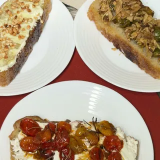 Dois pratos servidos: um com tomate confit sobre coalhada e outro com cobertura de ervas